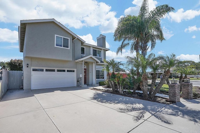 traditional-style home with stucco siding, fence, concrete driveway, a garage, and a chimney