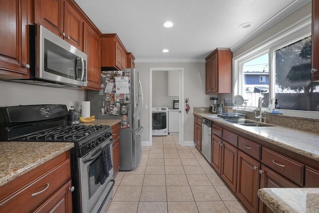 kitchen featuring crown molding, appliances with stainless steel finishes, light tile patterned flooring, washer / clothes dryer, and a sink