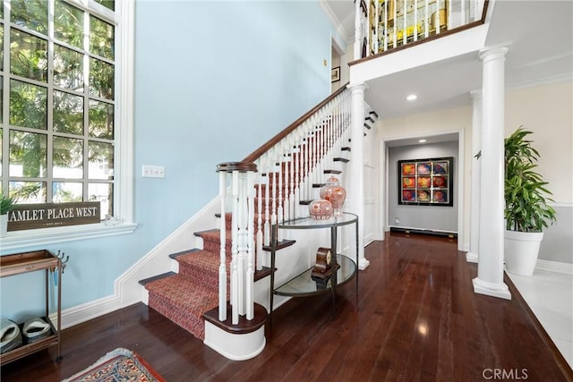 stairs featuring a healthy amount of sunlight, wood finished floors, and decorative columns