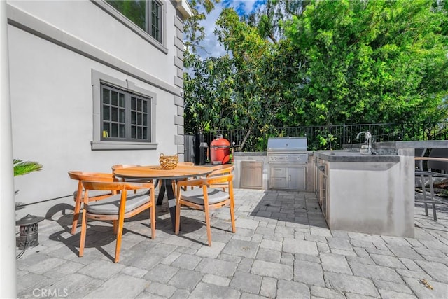 view of patio featuring outdoor dining space, fence, outdoor wet bar, area for grilling, and grilling area