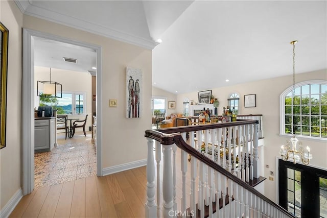 hallway with visible vents, an upstairs landing, light wood finished floors, baseboards, and vaulted ceiling