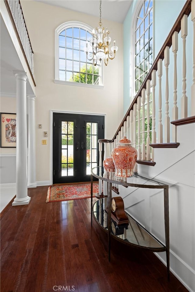 foyer featuring a chandelier, stairway, ornate columns, and wood-type flooring