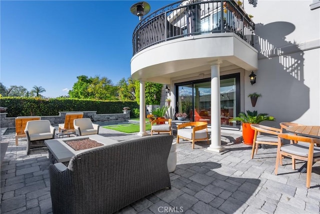 view of patio featuring an outdoor living space with a fire pit and a balcony