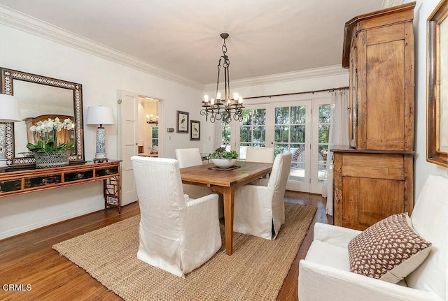 dining area with crown molding, a notable chandelier, and wood finished floors