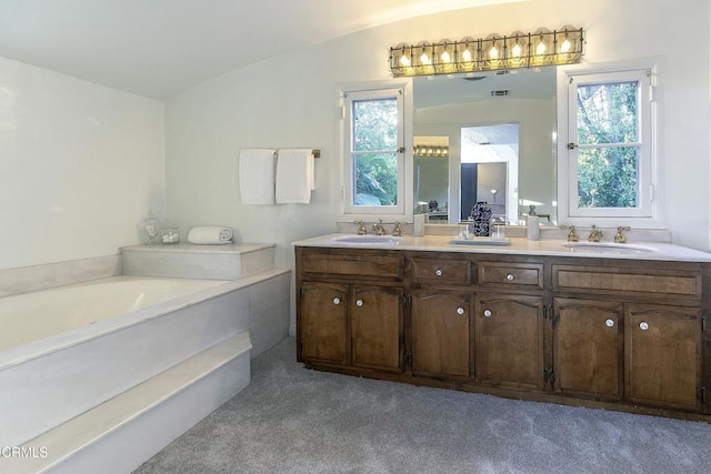 bathroom with a garden tub, carpet, lofted ceiling, and a sink