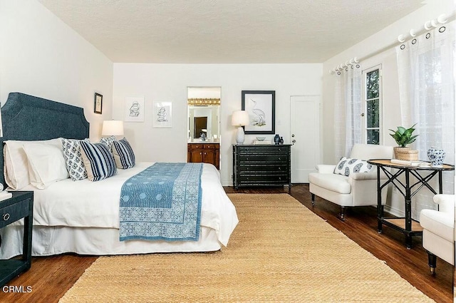 bedroom with connected bathroom, wood finished floors, and a textured ceiling