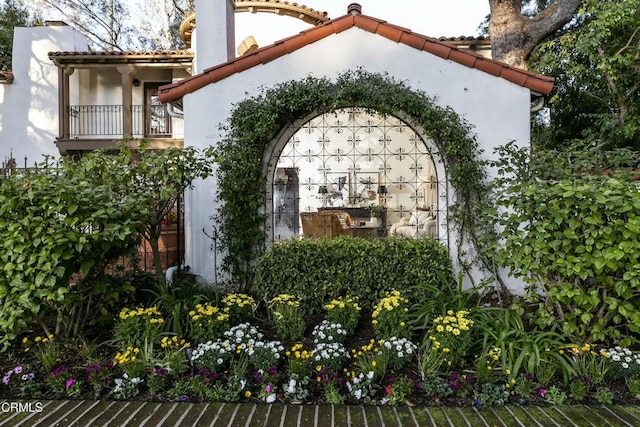 exterior space featuring a tiled roof, a balcony, and stucco siding