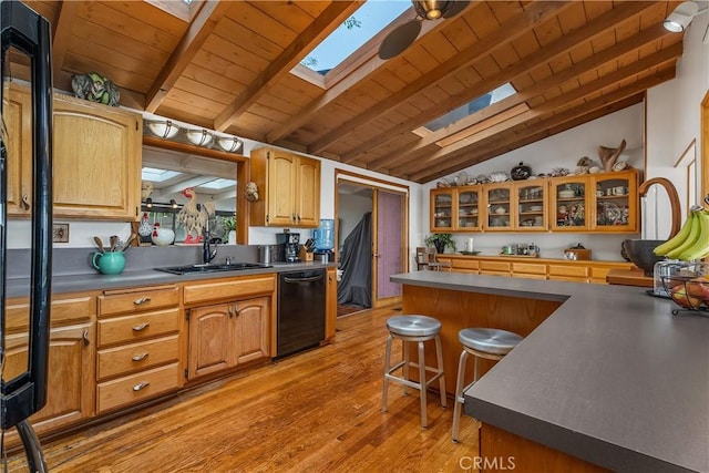 kitchen featuring glass insert cabinets, light wood-type flooring, black dishwasher, vaulted ceiling with skylight, and a sink