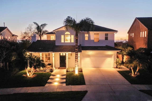 traditional-style house with a tile roof, an attached garage, and driveway