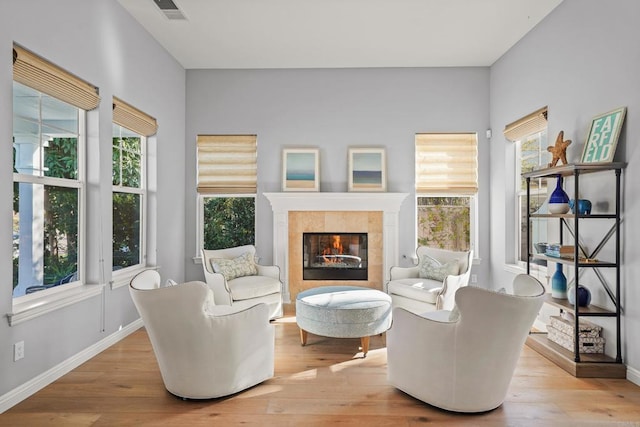 living area with a fireplace, visible vents, light wood-style floors, and baseboards