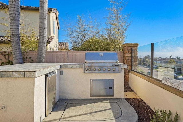 view of patio with area for grilling, a grill, and fence