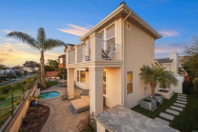 rear view of property with stucco siding, a patio, a fenced backyard, a fenced in pool, and a balcony