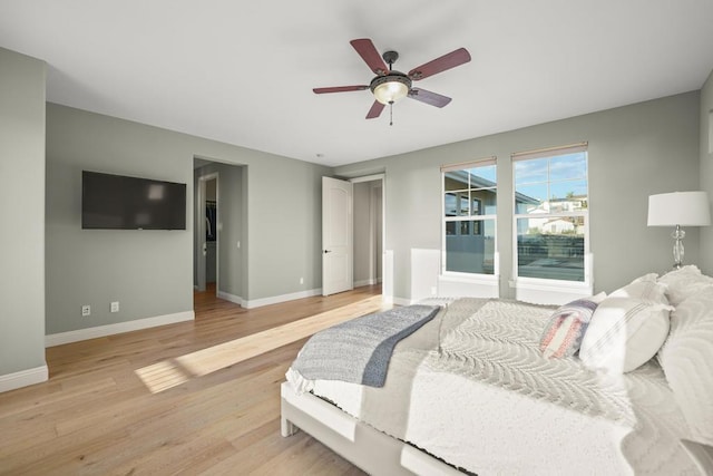 bedroom featuring baseboards, light wood-style floors, and a ceiling fan