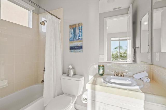 bathroom featuring visible vents, shower / bath combination with curtain, toilet, and vanity