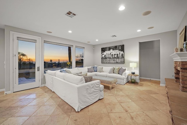 living room with recessed lighting, a fireplace with raised hearth, visible vents, and baseboards