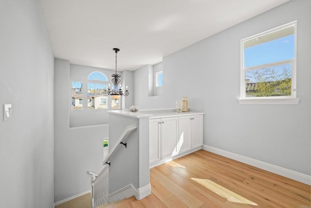 interior space with an inviting chandelier, an upstairs landing, light wood-style floors, and baseboards