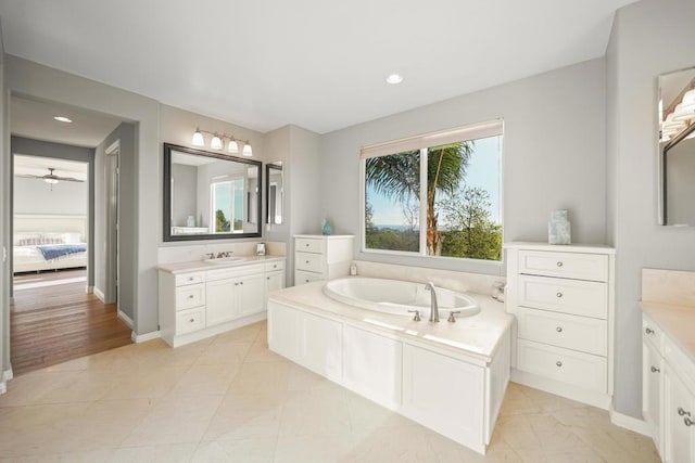 ensuite bathroom with a sink, two vanities, a bath, and ensuite bathroom