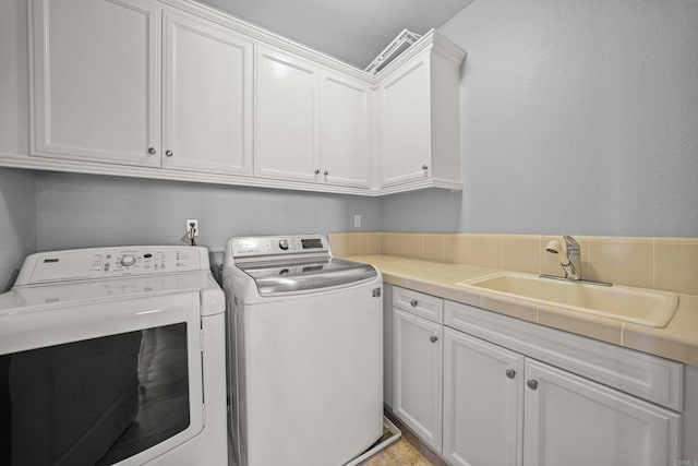 laundry area featuring cabinet space, independent washer and dryer, and a sink