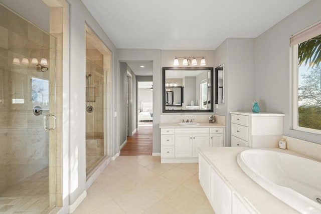 bathroom featuring baseboards, a stall shower, vanity, and a bath