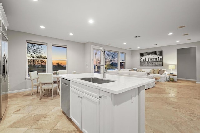 kitchen featuring a center island with sink, a sink, stainless steel dishwasher, white cabinetry, and recessed lighting