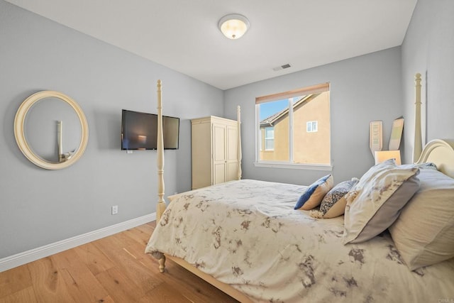 bedroom with visible vents, baseboards, and wood finished floors