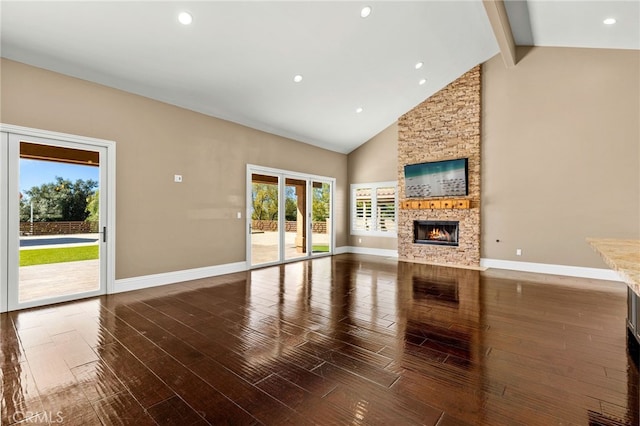 unfurnished living room featuring baseboards, beamed ceiling, a stone fireplace, wood finished floors, and high vaulted ceiling