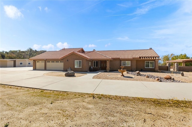 view of front of home featuring stucco siding, driveway, a tile roof, and a garage