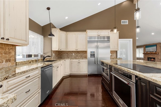 kitchen featuring visible vents, light stone countertops, lofted ceiling, stainless steel appliances, and a sink