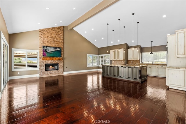 kitchen with beam ceiling, plenty of natural light, dark wood-style floors, open floor plan, and a fireplace