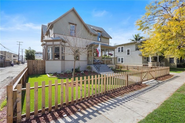 view of front of house featuring a front lawn, a porch, and a fenced front yard