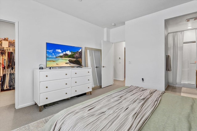 bedroom with visible vents, connected bathroom, a walk in closet, light carpet, and a closet