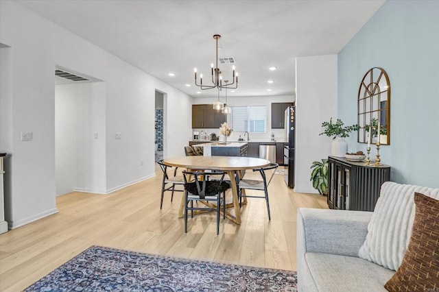 dining area with light wood finished floors, visible vents, recessed lighting, and a chandelier