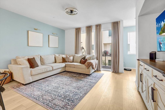 living area featuring baseboards and light wood finished floors