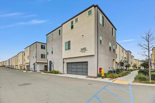 view of property with a residential view, an attached garage, and central AC