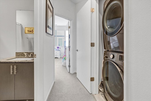 laundry room with laundry area, light colored carpet, stacked washer / drying machine, and a sink