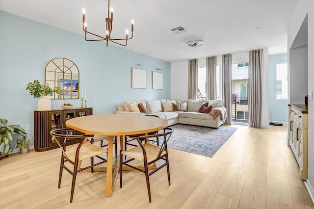 dining room featuring visible vents, light wood-style floors, and a notable chandelier