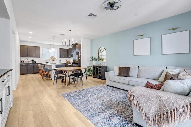 living area with an inviting chandelier, recessed lighting, light wood-style floors, and visible vents