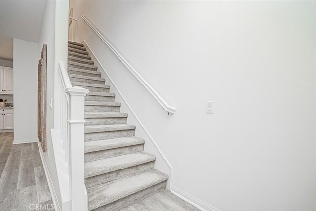 stairway with baseboards and wood finished floors