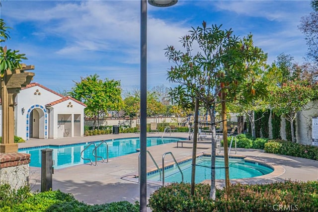 community pool with a patio area and fence