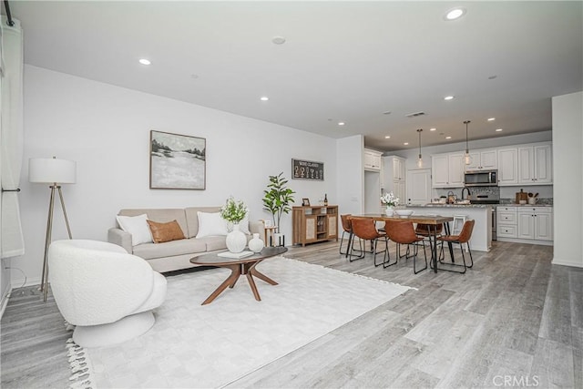 living room with recessed lighting, light wood-type flooring, baseboards, and visible vents