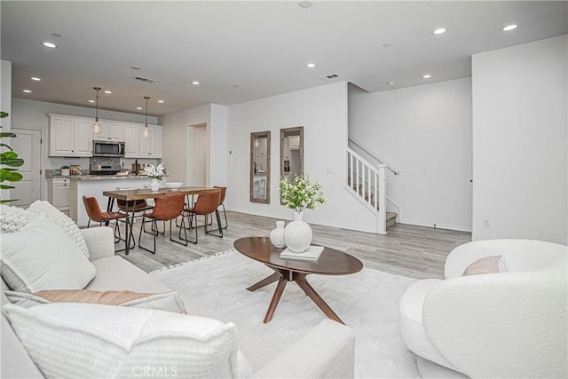 living room with stairway, recessed lighting, light wood-type flooring, and visible vents