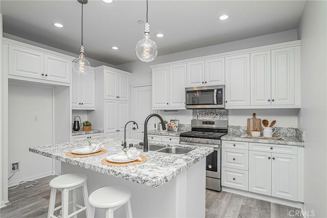 kitchen with a sink, white cabinets, light wood finished floors, and stainless steel appliances