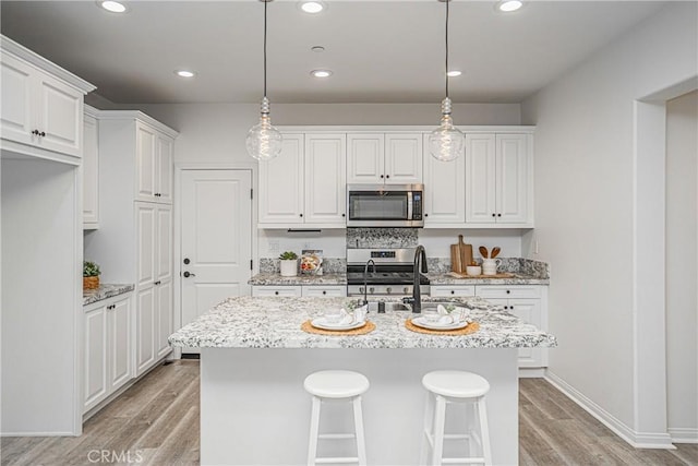 kitchen featuring light wood-style flooring, white cabinets, appliances with stainless steel finishes, and a sink