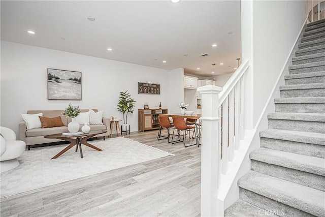 living room with stairs, light wood-style flooring, recessed lighting, and visible vents