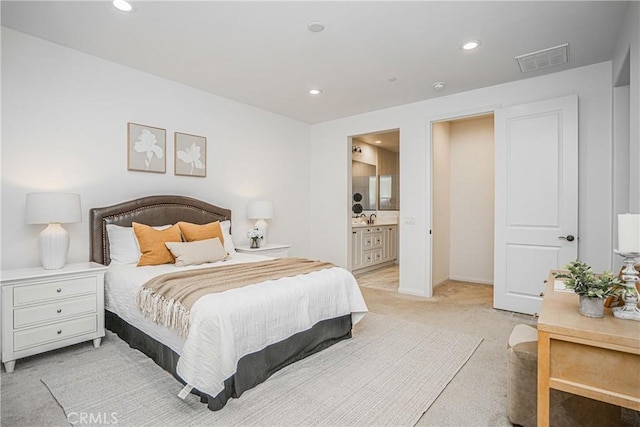 bedroom with visible vents, light carpet, recessed lighting, ensuite bath, and a sink