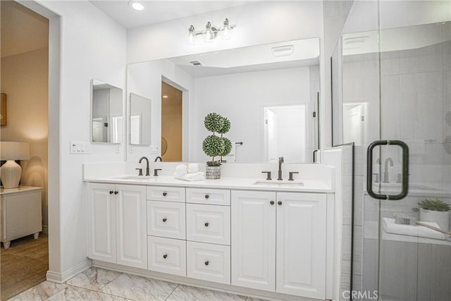 full bathroom featuring a shower with door, marble finish floor, double vanity, and a sink