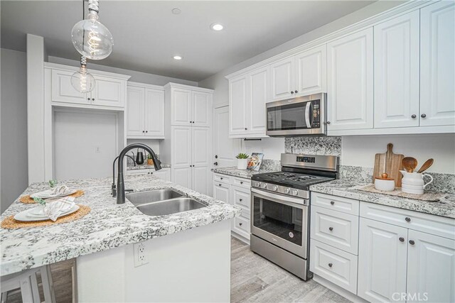 kitchen with white cabinetry, light wood-type flooring, appliances with stainless steel finishes, and a sink