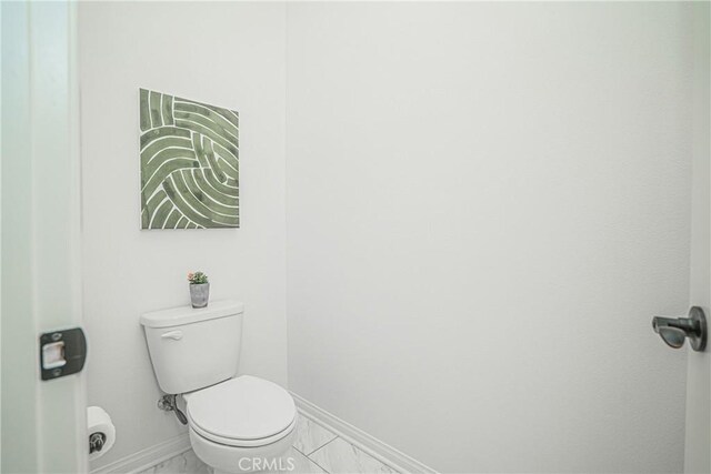 bathroom featuring toilet, baseboards, and marble finish floor