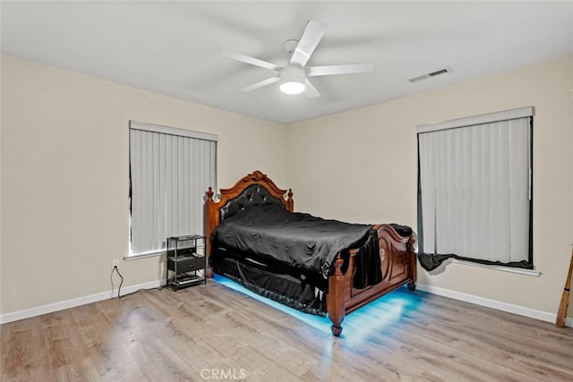 bedroom with a ceiling fan, wood finished floors, visible vents, and baseboards