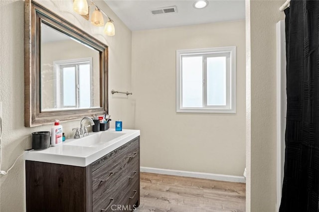 bathroom featuring visible vents, plenty of natural light, baseboards, and wood finished floors